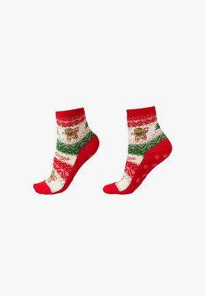 Červené a bílé ponožky se vzory perníčků a cukrovinek, s zelenými akcenty a protiskluzovými tečkovanými podrážkami pro lepší uchopení.