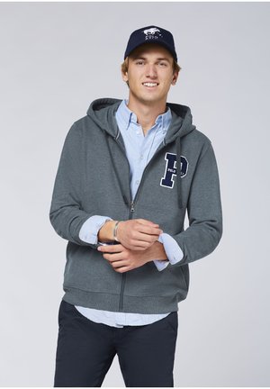 Gray zip-up hoodie with a navy "P" logo, layered over a light blue shirt, paired with dark pants. Features a drawstring hood and front pockets.