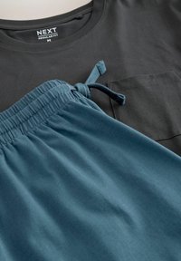 Black cotton t-shirt with a pocket, paired with teal drawstring shorts featuring an elastic waistband and smooth texture.