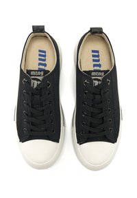 Zapatillas de lona negras con cordones negros, puntera de goma blanca y plantilla de tacto texturizado en color marrón claro que presenta el logo de la marca. Forma redondeada, diseño minimalista.