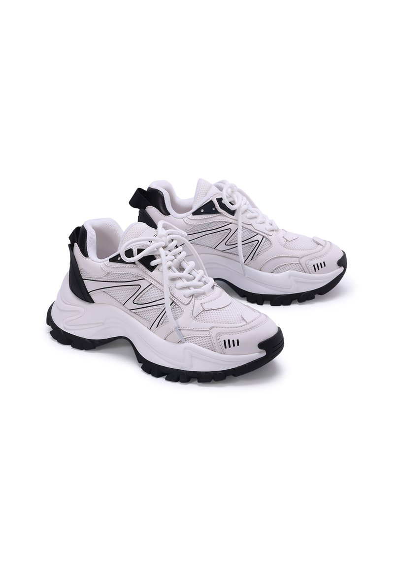 Scarpe sportive bianche con accenti neri, tomaia in rete e materiale sintetico, suola in gomma spessa e design con lacci, caratterizzate da un tassello sul tallone.
