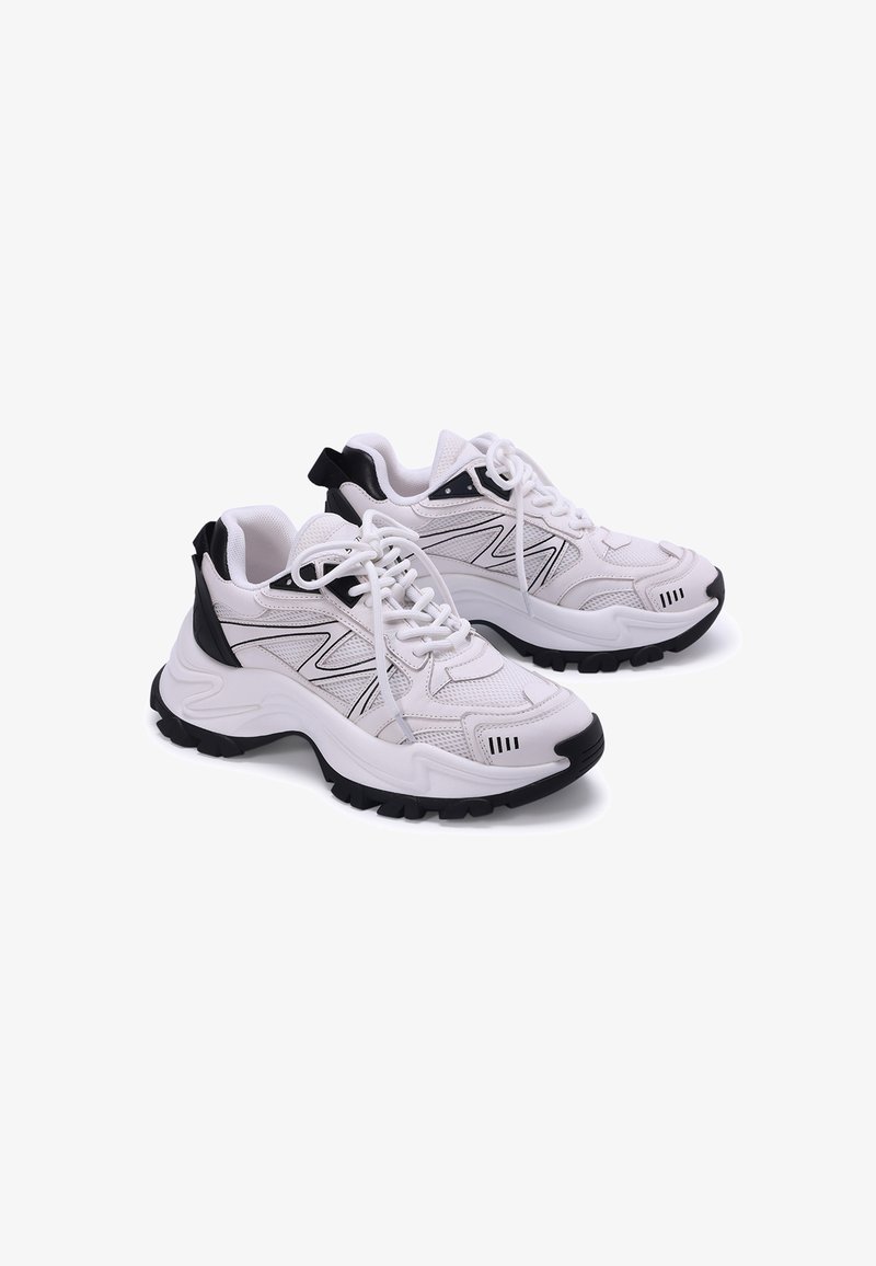 Zapatillas deportivas blancas con acentos negros, parte superior de malla y sintético, suela de goma gruesa y diseño de cordones con una lengüeta en el talón.