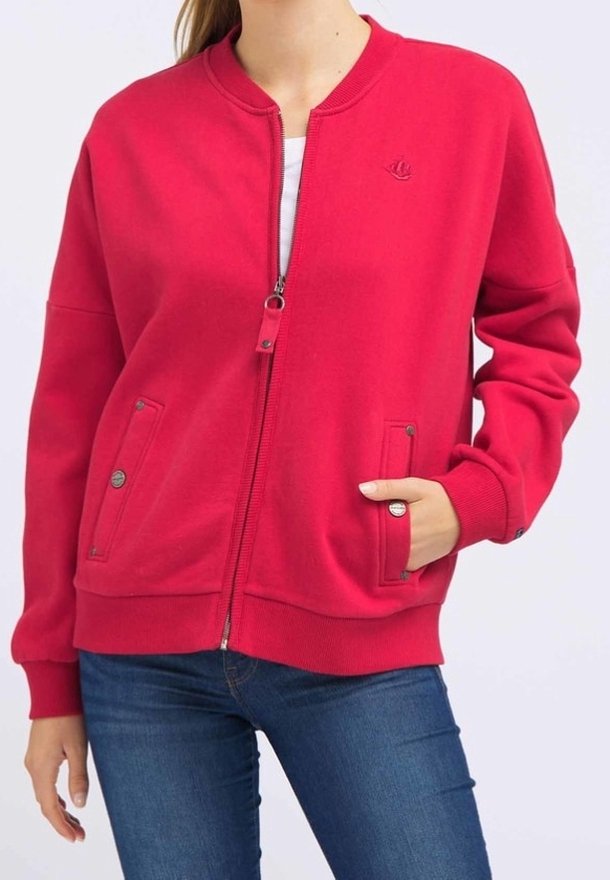 Veste zippée rouge avec col côtelé, deux poches avant à fermeture à pression, et coupe ajustée. Tissu en coton lisse avec un détail logo.