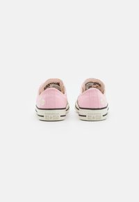 Růžové plátěné tenisky s bílým prošíváním a květinovou výšivkou na patě. Černá gumová podrážka s klasickým brandingem Converse na boku.