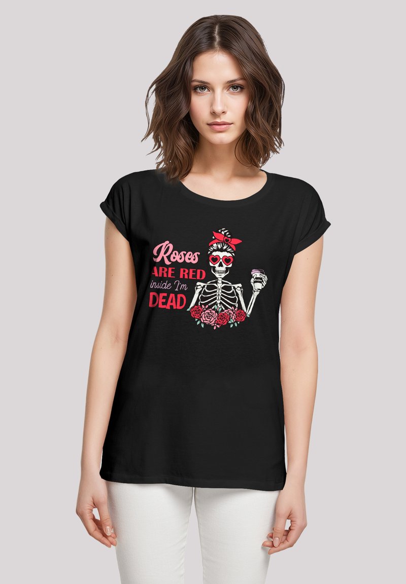Schwarzes T-Shirt mit hochgekrempelten Ärmeln, das ein Grafikmotiv eines Skeletts mit einem roten Bandana und herzförmigen Sonnenbrillen zeigt, umgeben von rosa Rosen.