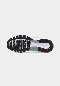 Σόλα παπουτσιού τρεξίματος Nike με μαύρη και πράσινη λαστιχένια τάπα σε λευκή ενδιάμεση σόλα, ορατό λογότυπο Nike κοντά στη φτέρνα, σε ανοιχτό γκρι φόντο.