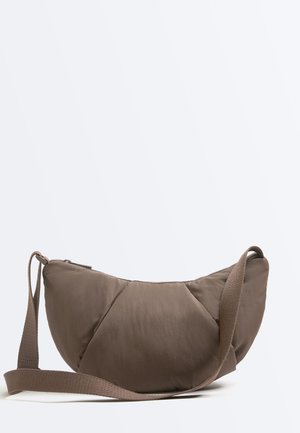 Bruine, halve maanvormige crossbodytas met verstelbare band en ritssluiting bovenaan, afgebeeld tegen een effen lichte achtergrond.