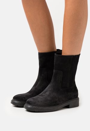 Stivali neri in suede alla caviglia con pannelli elastici laterali, punta arrotondata e tacco medio, caratterizzati da una finitura testurizzata e una suola in gomma resistente.