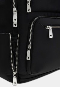Black textured backpack featuring multiple silver zippers with branded pulls, a prominent logo, and spacious compartments for organization.
