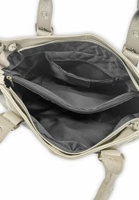 Sac à main en cuir beige avec une surface texturée, comprenant un compartiment zippé et deux poches ouvertes à l'intérieur. Doublure en tissu noir.