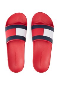 Sandales à enfiler rouges avec semelle texturée, présentant des bandes colorées bleu marine, rouge et blanche audacieuses sur le dessus. Marque en relief sur la semelle.