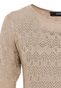 Top de punto beige hecho de un material texturizado que presenta un patrón geométrico con ligeros destellos. Escote redondo clásico y mangas cortas.
