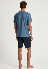 Blauwe t-shirt met korte mouwen en een zwarte kraag, gecombineerd met donkerblauwe shorts. Casual stof, eenvoudig ontwerp, zachte textuur.