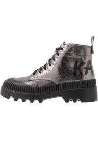 Botas de tobillo metálicas plateadas con acabado texturizado, suela de goma negra, bordes acanalados distintivos y diseño con cordones con detalle de marca.