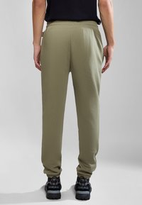 Olive green joggers with a relaxed fit, elastic waistband, and cuffed ankles, paired with black textured sneakers.