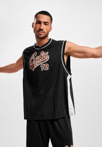 Haut de sport sans manches noir avec des accents blancs et un imprimé graphique. Le tissu semble léger, avec une coupe décontractée, idéal pour un vêtement de sport.