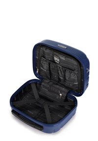 Valigia rigida blu navy con esterno testurizzato, interno in tessuto nero dotato di più scomparti, una tasca con zip e cinghie di sicurezza.