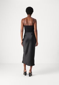 Robe en satin noir avec un corsage ajusté et des bretelles spaghetti réglables, dotée d'une jupe fluide et d'une texture lisse et soyeuse.