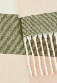 Vævet tæppe med striber i lys pink, fløde og oliven. Afsluttet med hvide frynser. Blød tekstur med et fiskebensmønster.