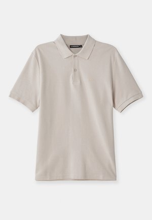 Beige polo skjorta i bomull, med en klassisk krage, korta ärmar och en diskret broderad logotyp på vänster bröst.