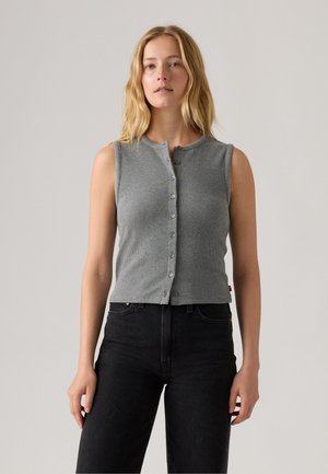 Top grigio senza maniche a coste con scollo rotondo e chiusura frontale a bottoni. Indossato con jeans neri a vita alta. Design e texture semplici.