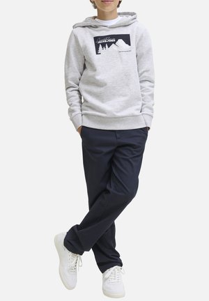 Sweat à capuche gris avec un graphique sur le devant représentant des montagnes et des arbres, associé à un pantalon marine et des baskets blanches. Style décontracté, coupe confortable.