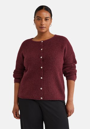 Burgundský pletený cardigan s okrúhlym výstrihom, dlhými rukávmi a šiestimi bielymi gombíkmi na prednej strane. Mäkká textúra, voľný strih.
