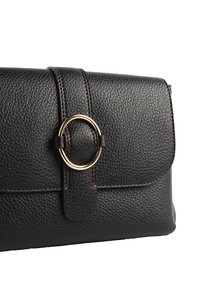 Borsa in pelle nera texturizzata con un accento circolare dorato, dotata di una chiusura a patta ordinata e dettagli di cucitura in contrasto.