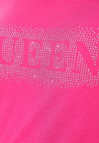 Jasně růžová látka s třpytivými stříbrnými hroty tvořícími stylizovaný vzor nebo textový design po celé ploše.