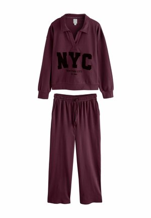 Burgundy loungewear set featuring a pullover with a collar and large "NYC" print, paired with elastic waistband pants. Soft fabric texture.