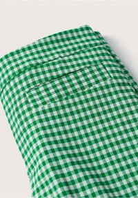 Tissu à motif vichy vert et blanc avec une poche arrière ornée d'une bordure rayée assortie. Texture lisse et finition soignée.