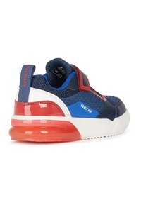 Baskets en tissu bleu et marine avec des accents rouges, bande Velcro, talon rouge brillant et semelle blanche. Marquage Geox notable sur le côté.