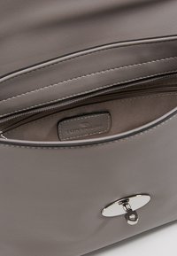 Szara torebka z sztucznej skóry o gładkiej fakturze, srebrne okucia, wewnętrzna kieszeń na zamek oraz metka z wytłoczonym napisem "Toni Tailor."