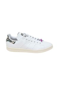 Fehér bőr sneaker, textúrált fekete és kék mintás sarokkal, lila fűző kiemeléssel és perforált oldalakkal. Klasszikus alacsony fazon jellemzi.