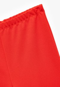 Røde atletiske shorts med en glat overflade og elastisk talje. Har et enkelt design uden yderligere mønstre eller detaljer.