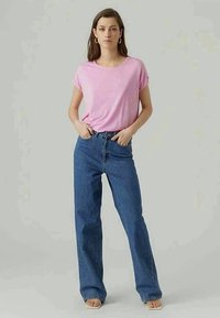 T-shirt de manga curta rosa claro, combinado com jeans de denim azul de cintura alta, apresentando um corte descontraído e design de perna reta.