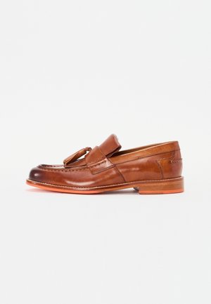 Brun læder loafersko med rund tå, dekorativ kvast og subtil syning. Har en lav hæl og en kontrasterende orange sål.