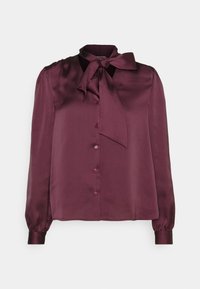 Blusa di satin bordeaux con colletto a fiocco, chiusura con bottoni, maniche lunghe e polsini elasticizzati, caratterizzata da una texture liscia e lucida.