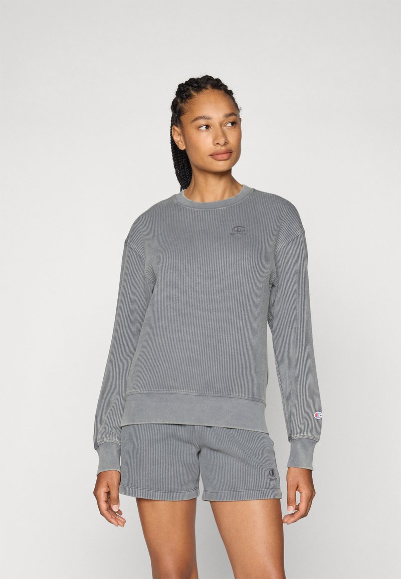 Grå ribbestrikket hettegenser med lange ermer og rund halslinning, kombinert med matchende shorts. Har en liten logo på brystet og låret.