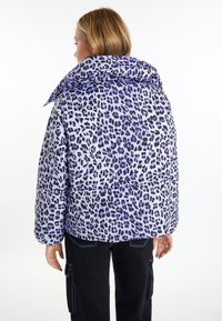 Jachetă pufosă mov cu imprimeu leopard negru, guler mare, design matlasat și tiv prelungit pe spate. Asortată cu pantaloni negri.