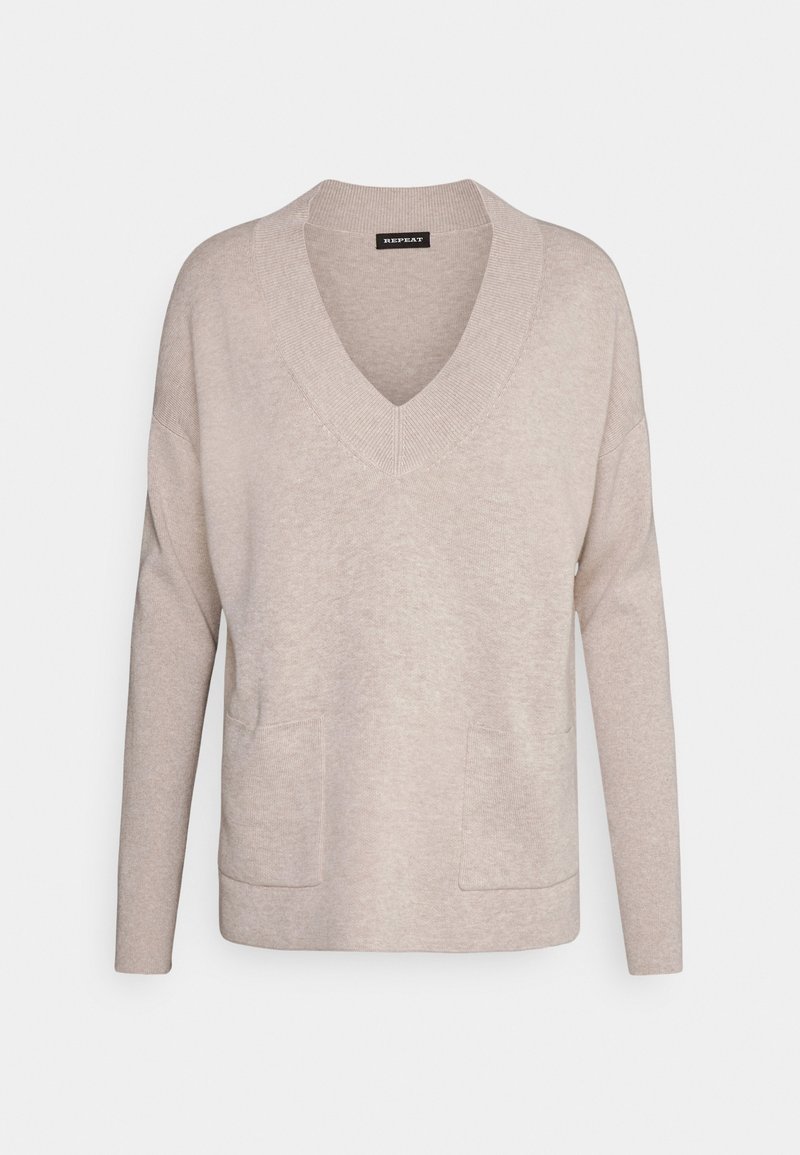 Pull beige à col en V et manches longues avec col côtelé et deux poches devant, présenté sur un fond uni.