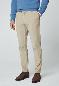 Beiga kordflodbyxor med slim fit, med sidofickor och rak framdel. Bärs med en blå tröja och bruna mockaskor.