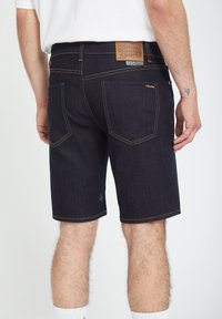 Donkere blauwe denim shorts met contrasterende stiksels, vijf zakken en een leren label op de tailleband met het merklogo.
