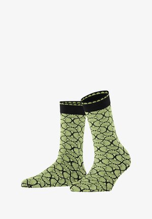 Chaussettes vertes à motif avec un design de feuilles sur fond noir, dotées d'une bordure côtelée noire et d'une texture lisse.