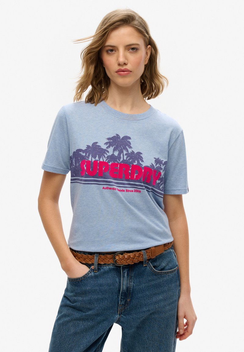 Jasnoniebieska koszulka z grafiką palmy w kolorze fioletowym oraz wyboldowanym czerwonym logo "SUPERDRY". Prosty krój typu crew neck z krótkimi rękawami.