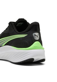 Zapatilla deportiva negra con parte superior texturizada, acentos verdes y una suela acolchada blanca. Presenta un logo de Puma en el talón y líneas de diseño elegantes.