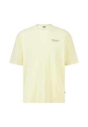 Bleekgele T-shirt met korte mouwen en ronde hals met kleine zwarte cursieve tekst op de bovenste linkerborst met de tekst "Willesborg."