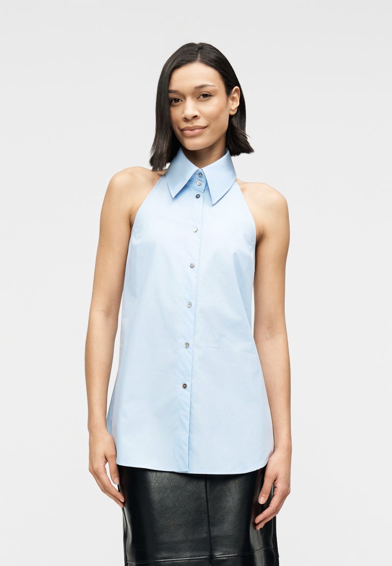 Φωτεινό γαλάζιο αμάνικο πουκάμισο με μεγάλο γιακά, κουμπιά στο μπροστινό μέρος και διακριτική γυαλάδα. Διαθέτει ομαλή υφή και σχεδιασμό με άνετη εφαρμογή.