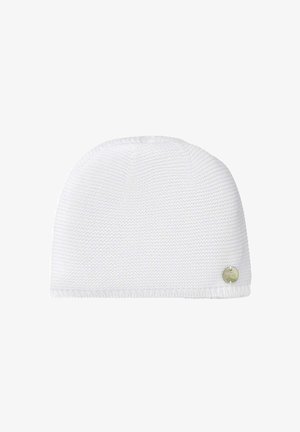 Bonnet blanc en tricot avec une petite étiquette logo métallique ronde près du bord inférieur, présenté sur un fond blanc uni.