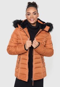 Orange padded jacket with a removable black fur-lined hood, zippered pockets, and ribbed cuffs, worn over a black turtleneck sweater.
